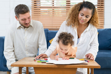 Happy parents playing with their adorable baby at home. Mom and dad looking at their baby who drawing on paper with pencil in cozy living room. Creative education. Early development
