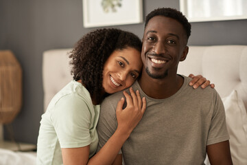 Young multiracial couple smiling in their bedroom in the morning
