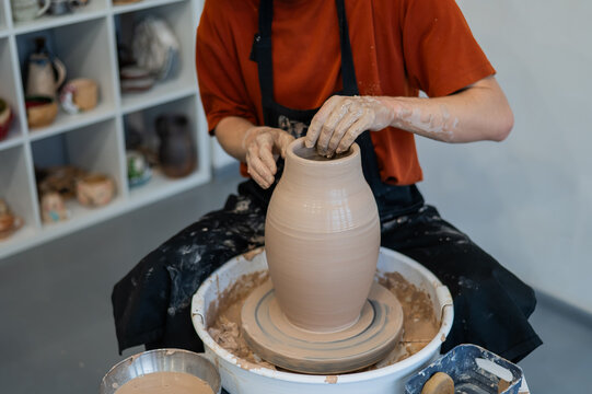 Close-up of a potter's hands making a ceramic vase on a potter's wheel. 