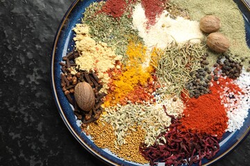 Different aromatic spices on dark textured table, top view
