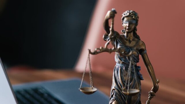 Statue of justice with scales and laptop in a modern office cubicle.  Lawyer's office. The concept of legal law, counseling and the concept of justice.