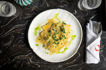 Portion of italian ravioli dumplings dish with sauce and green oil