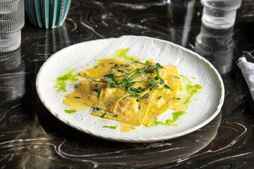 Portion of italian ravioli dumplings dish with sauce and green oil