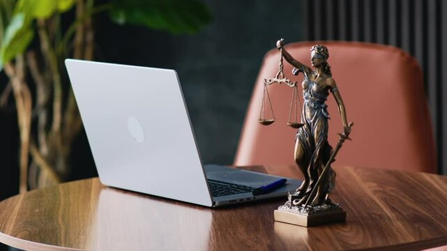 Statue of justice with scales and laptop in a modern office cubicle.  Lawyer's office. The concept of legal law, counseling and the concept of justice.