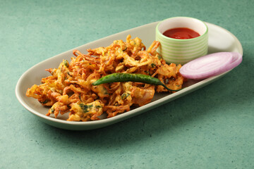 deep fried onion pakoda with tomato sauce and green chilly