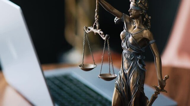 A statue of justice with a laptop on a lawyer's desk in a modern office. The concept of justice and legal consultations.
