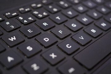 Black laptop backlit keyboard close up. Most keys are out of focus making it a great background picture.