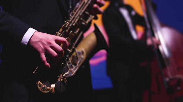 Concert view of saxophonist musician, saxophone sax player with vocalist and musical band during jazz orchestra show performing music on a scene in the stage lights, concert in a musical club hall