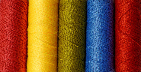 Spool of sewing thread, isolated on white background. Colored yarns used by factories in the clothing industry. Threads wound on the spool. Colored reels. Background and abstract image.