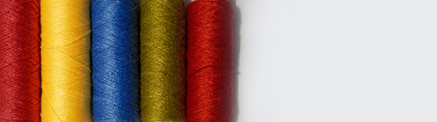 Spool of sewing thread, isolated on white background. Colored yarns used by factories in the clothing industry. Threads wound on the spool. Colored reels. Background and abstract image. Copy space.
