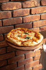 Holding portion of gourmet baked italian pizza margherita in hands