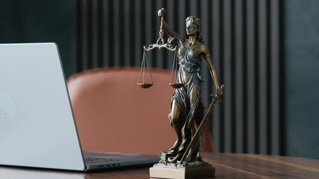 Statue of justice with scales and laptop in a modern office cubicle.  Lawyer's office. The concept of legal law, counseling and the concept of justice.