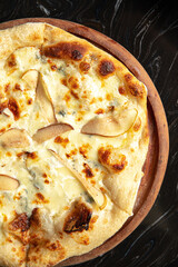 Portion of gourmet italian pizza with cheese and pears