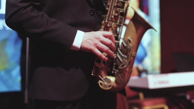 Concert view of saxophonist musician, saxophone sax player with vocalist and musical band during jazz orchestra show performing music on a scene in the stage lights, concert in a musical club hall