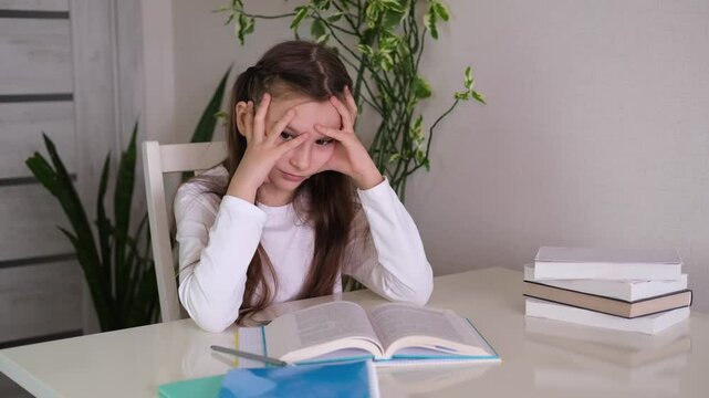 Little schoolgirl is upset and depressed. Depressed girl does not want to study, she has poor grades at school. Schoolgirl is tired in class and wants to sleep. Concept of education.