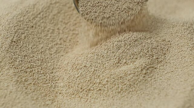 Dry yeast spilling out of spoon, macro slow motion.