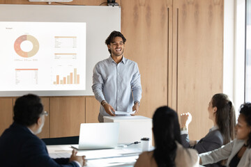 Cheerful Hispanic businessman, trainer or lecturer standing and speaking in front of group of...