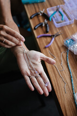 Hands hold the neck pendant. Woman made a pendant at a jewelry making workshop