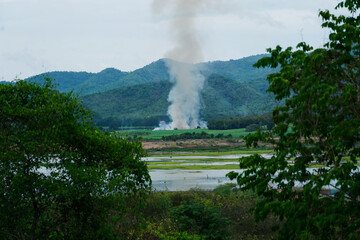 Fototapeta premium Many smoke cover corn agricultural fields with hill, farmer burning crops after harvest. stubble burning case of air pollution in summer.
