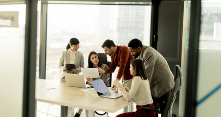 Team collaborates in modern office setting on innovative project with laptops and discussion