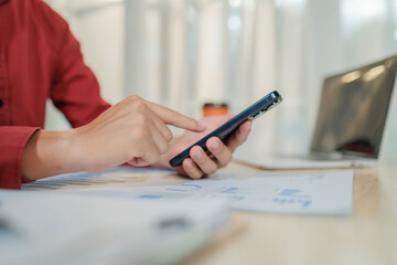 A focused businessperson works on summarizing annual performance results while multitasking by...