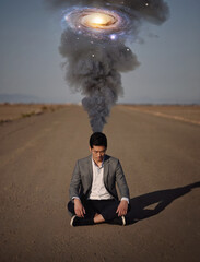 State of mind and mental health concept as a melancholic person sitting alone in the middle of a road. Man suffers burnout as a dark smoke comes out of head and transforms into a galaxy of thoughts