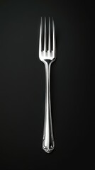 Elegant stainless steel fork placed on a solid black background showcasing its intricate design and shine