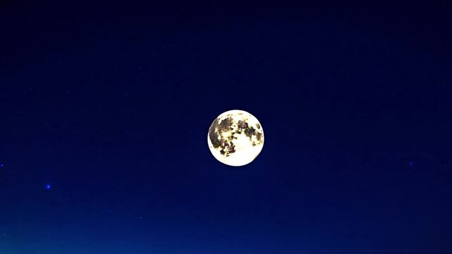 Bright full moon in dark night sky with stars and deep blue gradient sky