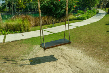 Empty swing on a tree in a park,wooden swing in a green park closeup view,Landscape view of green grass,backyard panoramic view on a beautiful sunny day..
