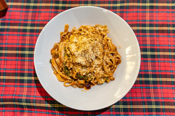 Cooked Tagliatelle pasta served with savory meat sauce and cheese in white plate on the table
