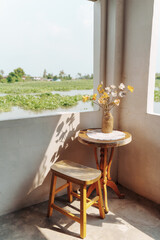 Artificial flower on wooden table and chair in peaceful cornor by river
