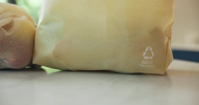 Groceries, recycling symbol and shopping bags on kitchen counter for eco friendly conservation. Ecology, reusable and sustainability with packets closeup in apartment for consumerism or zero waste