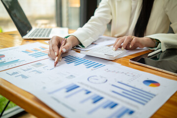 businesswoman is analyzing annual performance from lot of documents on table to improve marketing make her business more successful. businesswoman is checking business information from lot of document