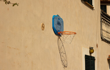 Minimalist image of a basketball hoop placed on an outdoor wall with the sun shining down © Answer 7