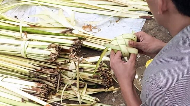 Slow motion. The hands of Asian man demonstrated a technique of wrapping young coconut leaves&nbsp;into&nbsp;Ketupat