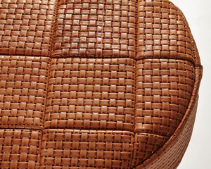 Woven leather upholstery creating textured surface on round furniture