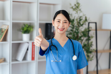 Female doctor or nurse standing and giving thumbs up gesture with stethoscope hanging on her neck.