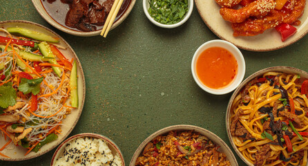Assorted Chinese dishes, sweet and sour chicken, beef in sauce, noodles, fried rice, salad and wooden chopsticks forming a frame around a central empty space. Copy space