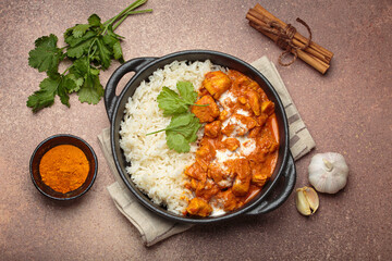 Aromatic Indian chicken tikka masala served with rice and coriander, turmeric, garlic, cinnamon sticks, traditional dish of India top view