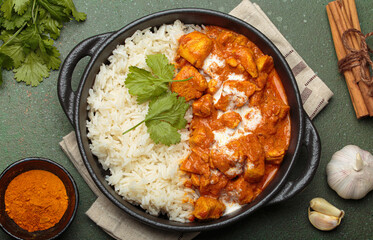Aromatic Indian chicken tikka masala served with rice and coriander, turmeric, garlic, cinnamon sticks, traditional dish of India top view