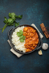 Indian chicken tikka masala in a creamy tomato sauce, served with basmati rice, fresh coriander and spices, traditional dish of India top view