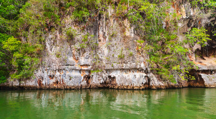 Samana bay view. A rocky cliff positioned by a tranquil green water