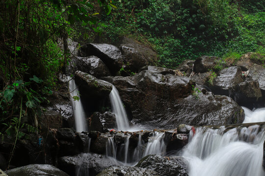 Cascading Falls: Water gracefully descends over rocky terrain, framed by verdant foliage, in a refreshing depiction of nature's power and serenity.