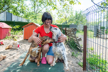 Group photo of rescued special needs dogs with their caregiver in their own fenced area  with sand and with their favorite toys for playing during free activities after therapies and exercises