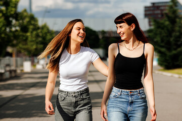 Obraz premium Two young women walking and laughing together in urban setting
