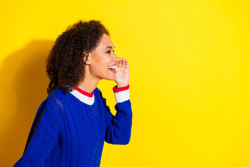 Side view of a cheerful young woman shouting while standing against a yellow background wearing a...