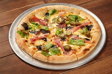 Delicious pizza with prosciutto, jalapeño, arugula, and truffle on wooden table