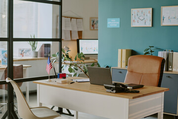 Organized modern office setting featuring tidy desk with a planner, flags, and technology elements neatly arranged with plants and wall decorations enhancing the space