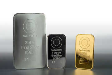 Gold and silver bars of various weights on a gray background.