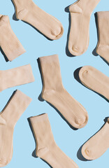 A variety of beige socks displayed on light blue background, highlighting textures and design in minimalism style, perfect for fashion and textile design projects. Vertical.